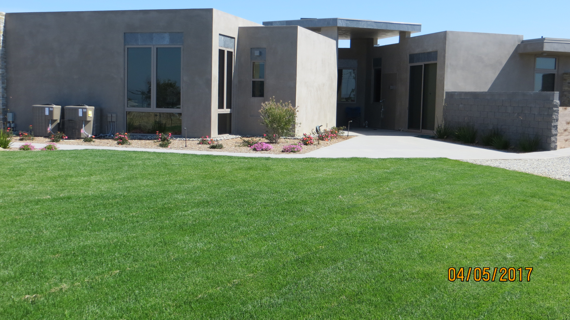 A Grey Color Concrete Home With Grass Lawn
