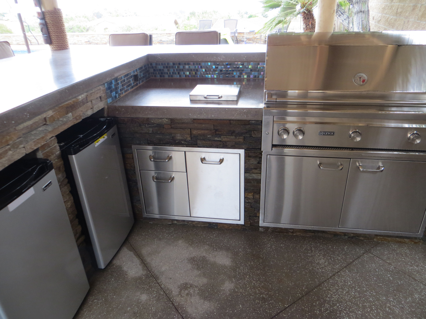 An Outdoor Kitchen Area With Stainless Steel Area