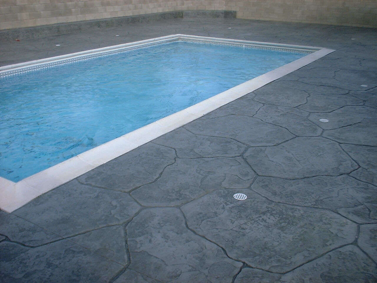 A Stamp Concrete Area WIth Drain Plugs by a Pool Area
