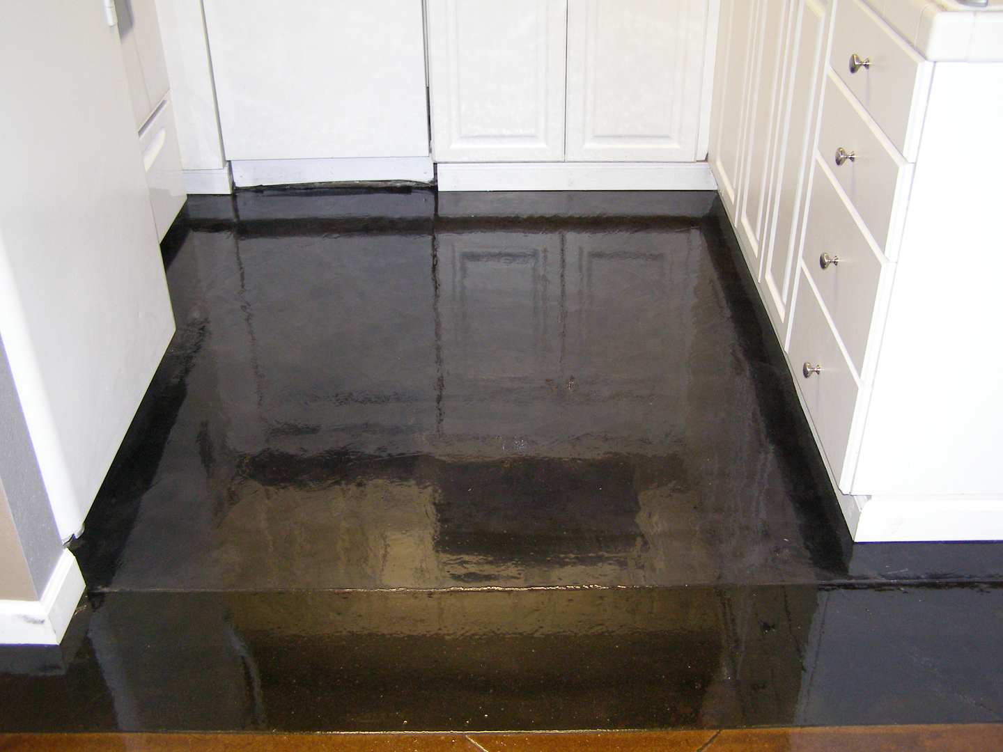 A Glazing Black Reflecting Flooring with white cabinets around